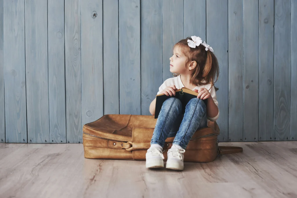girl sitting on a suitcase with a book with a curious expression
