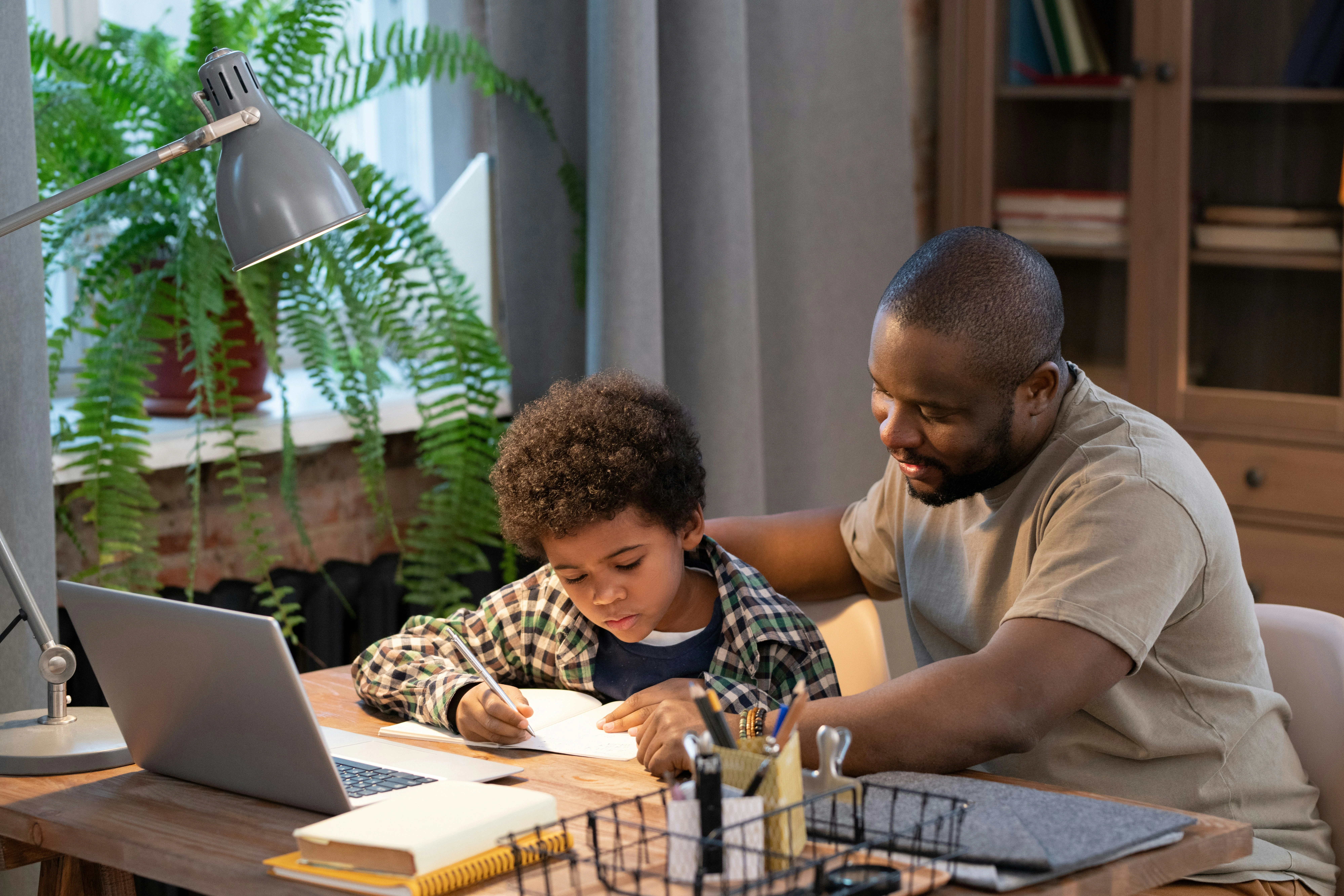 a dad and son working on homework at a table